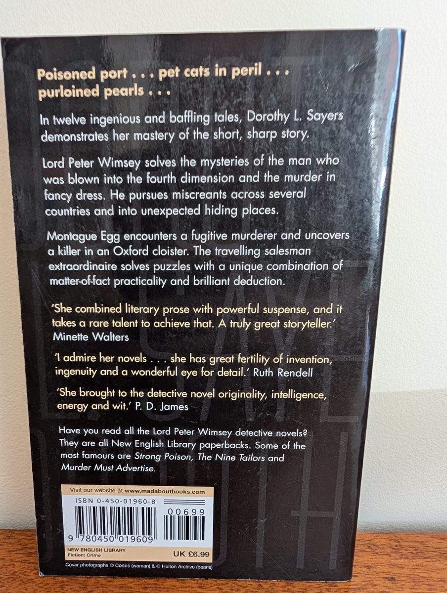 The back cover of the 1974 New English Library paperback of Hangman's Holiday by Dorothy L. Sayers. The black background carries a plot synopsis and pull quotes from Minette Walters, Ruth Rendell, and P. D. James in white text, with an ISBN barcode and UK price of £6.99.