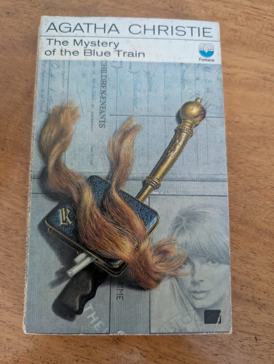 The Mystery of the Blue Train by Agatha Christie - Fontana/Collins 1972 paperback, dark cover with Tom Adams illustration of a Louis Vuitton case, gun, and flowing red hair