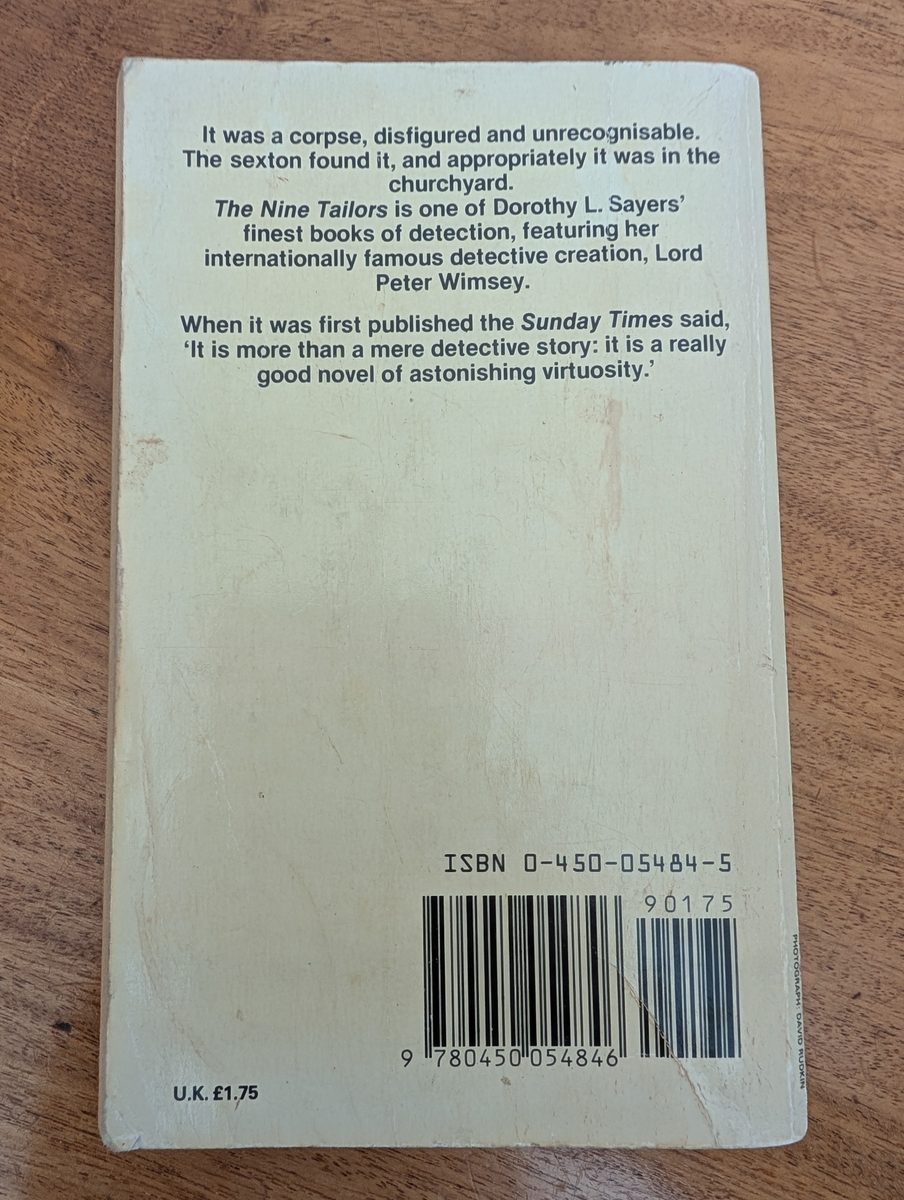 The back cover of the 1982 New English Library paperback of The Nine Tailors by Dorothy L. Sayers. The plain cream background carries a short plot synopsis and a Sunday Times review quote, with an ISBN barcode and UK price of £1.75. The cover shows general age-related wear and yellowing.
