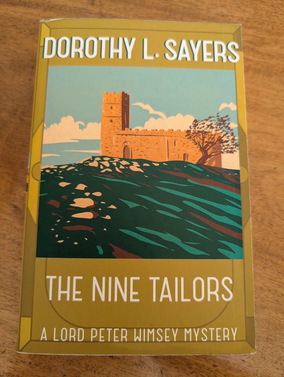 The front cover of the 2016 Hodder & Stoughton paperback edition of The Nine Tailors by Dorothy L. Sayers. The mustard-yellow cover features a bold Art Deco-style illustration of a stone fenland church tower rising against a blue sky, surrounded by a dark, moody landscape of water and earth. 'DOROTHY L. SAYERS' appears in white at the top, 'THE NINE TAILORS' at the bottom, and 'A LORD PETER WIMSEY MYSTERY' in smaller text below.