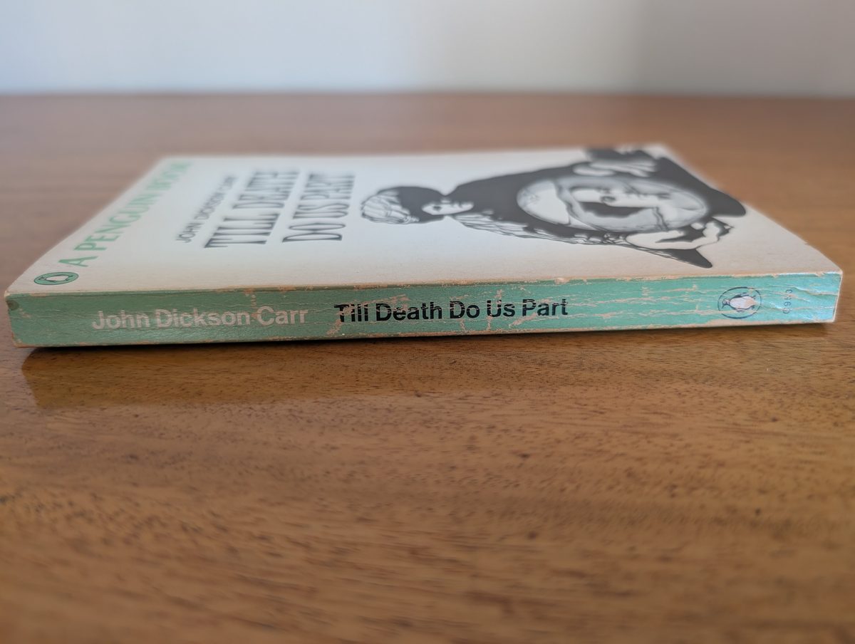 A photograph of the spine of the 1953 Penguin edition of John Dickson Carr's Till Death Do Us Part, showing some light, non-structural wear.